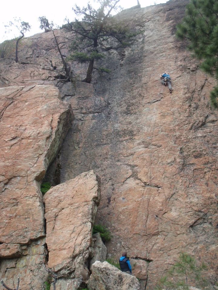 Climber high on a tall slab route with a partner belaying below